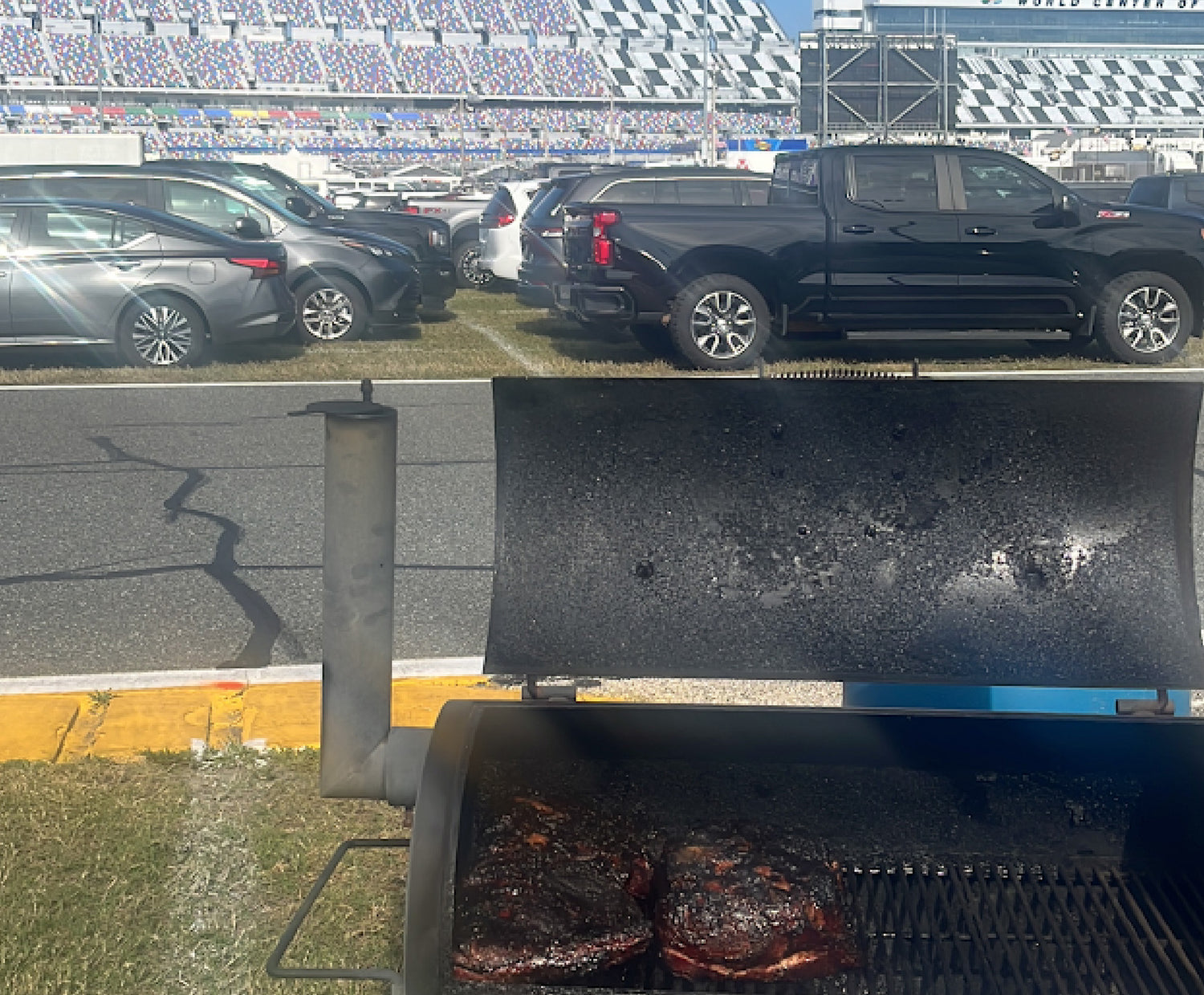 Smoker at a Nascar race filled with meat and grand stands in background